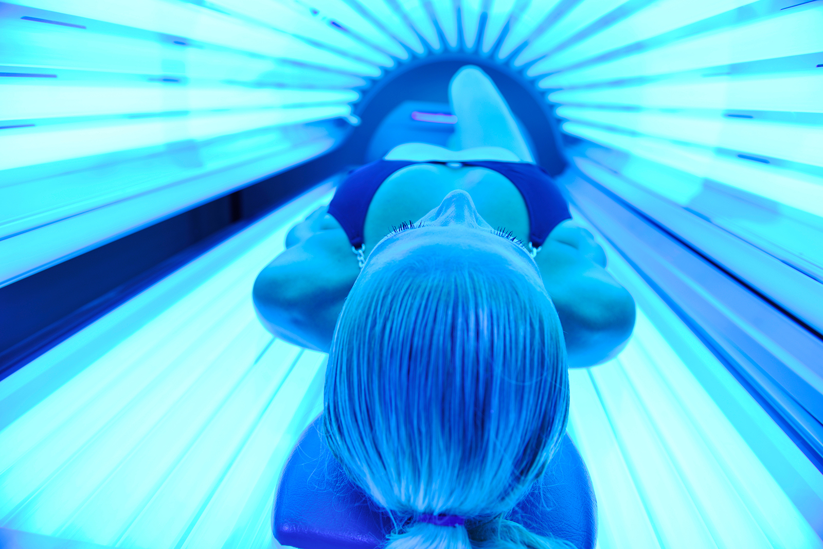 young woman at laying on tanning bed and get brown skin tone ready for summer